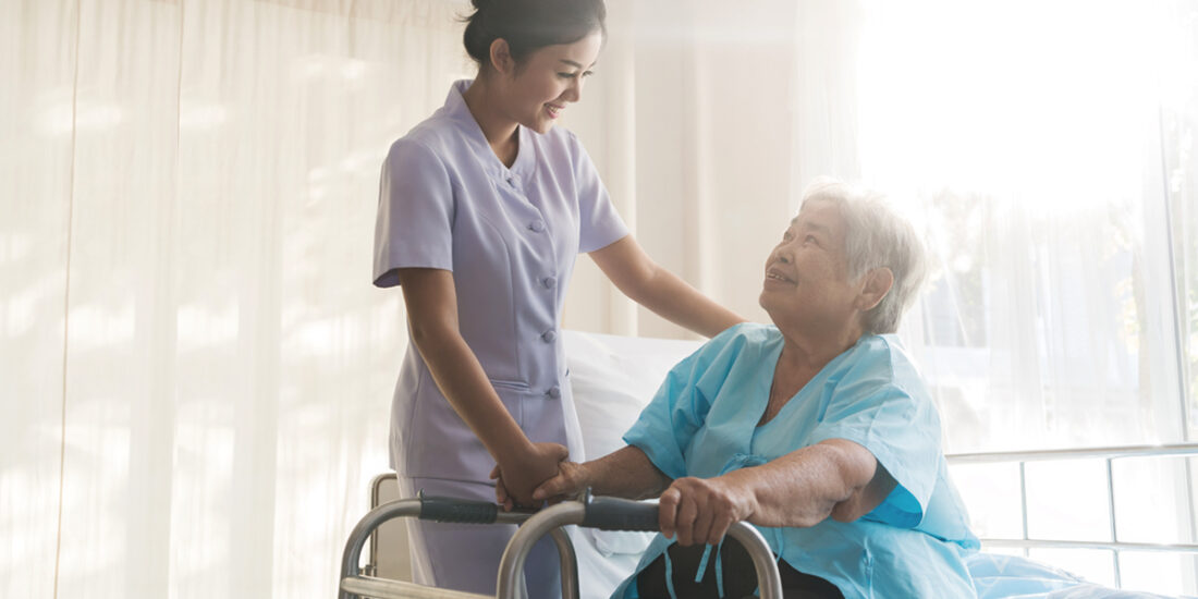 Asian young nurse supporting elderly patient disabled woman in u